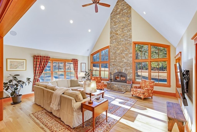 living room featuring a fireplace, plenty of natural light, high vaulted ceiling, and light wood-type flooring