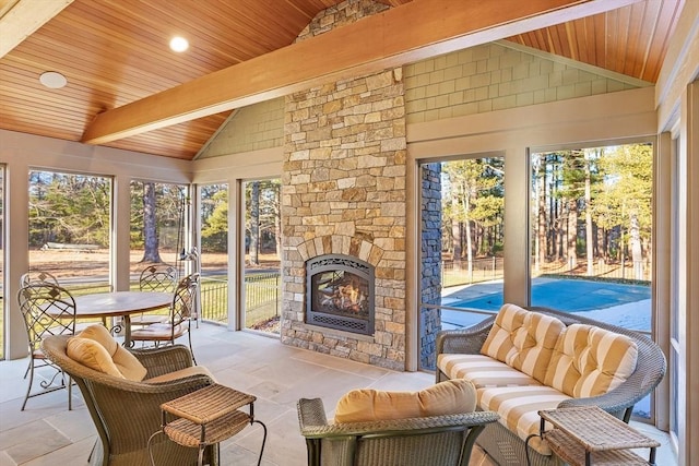 sunroom / solarium with an outdoor stone fireplace, vaulted ceiling with beams, and wood ceiling