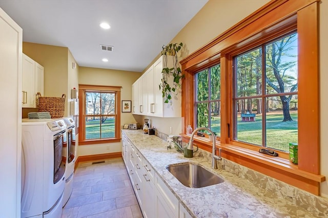 kitchen with white cabinetry, separate washer and dryer, sink, and light stone counters