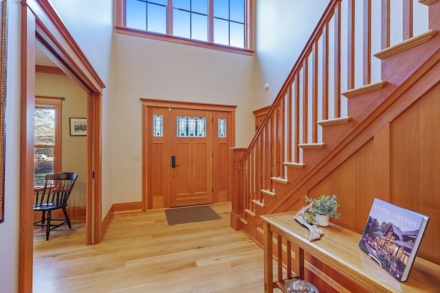 foyer with a towering ceiling and light wood-type flooring