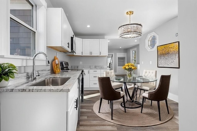 kitchen with sink, white cabinetry, hanging light fixtures, a chandelier, and dark wood-type flooring