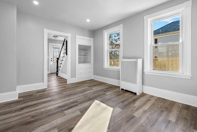 unfurnished room featuring built in features, dark hardwood / wood-style floors, and plenty of natural light