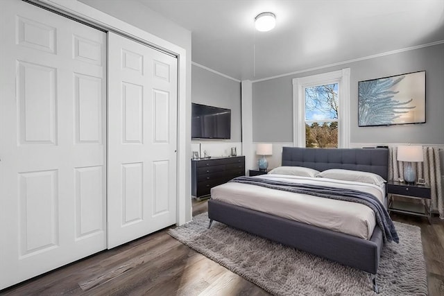 bedroom with dark wood-type flooring, ornamental molding, and a closet