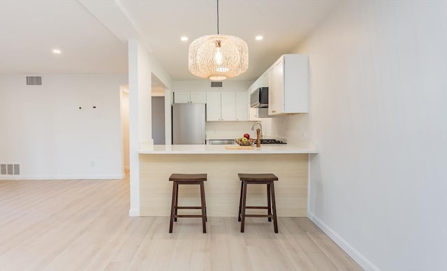 kitchen with a kitchen bar, light countertops, visible vents, and stainless steel appliances