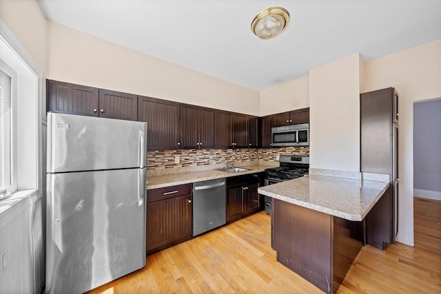 633 E Sixth St, Boston, MA 02127 - kitchen featuring appliances with stainless steel finishes, dark brown cabinets, a peninsula, a sink, and light wood-type flooring