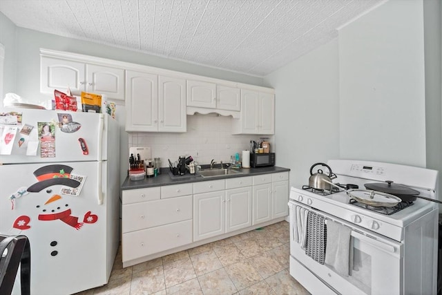 633 E Sixth St, Boston, MA 02127 - kitchen featuring white appliances, a sink, dark countertops, white cabinets, and decorative backsplash