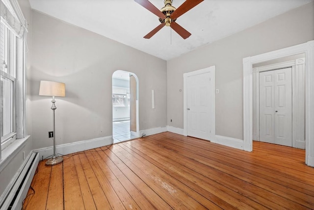 633 E Sixth St, Boston, MA 02127 - unfurnished bedroom featuring a baseboard radiator, arched walkways, light wood-style flooring, baseboards, and ceiling fan
