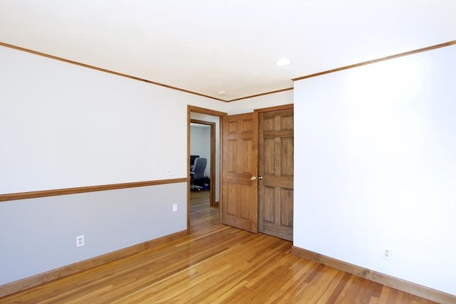 spare room featuring recessed lighting, baseboards, crown molding, and light wood finished floors