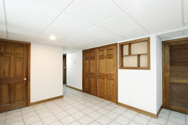 spare room with a paneled ceiling and baseboards