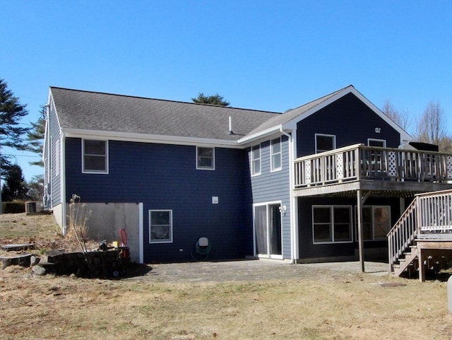 rear view of property with a shingled roof, stairs, and a deck