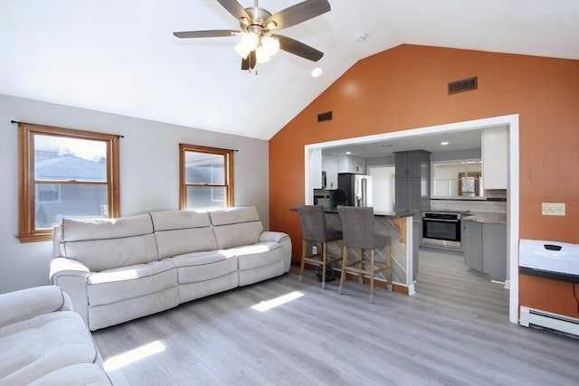 living room with vaulted ceiling, visible vents, light wood-style flooring, and a baseboard radiator