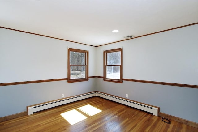 spare room with visible vents, ornamental molding, a baseboard radiator, and wood finished floors