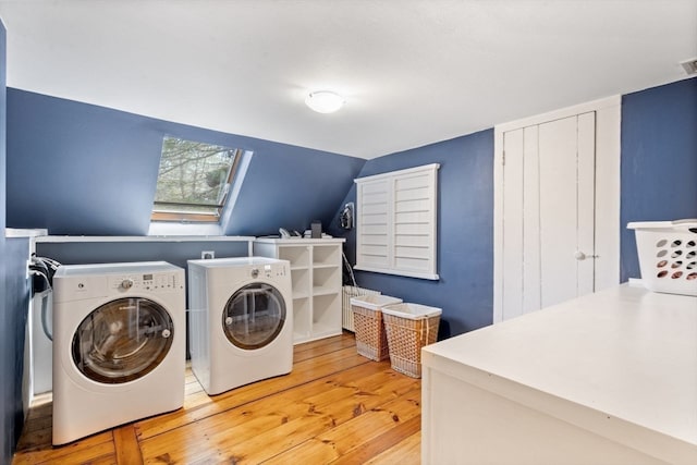 laundry room featuring a skylight, separate washer and dryer, and light wood-type flooring