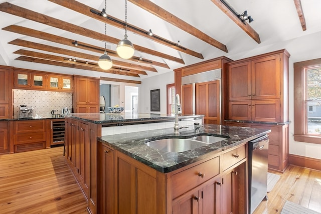 kitchen featuring a center island with sink, stainless steel dishwasher, tasteful backsplash, and beverage cooler