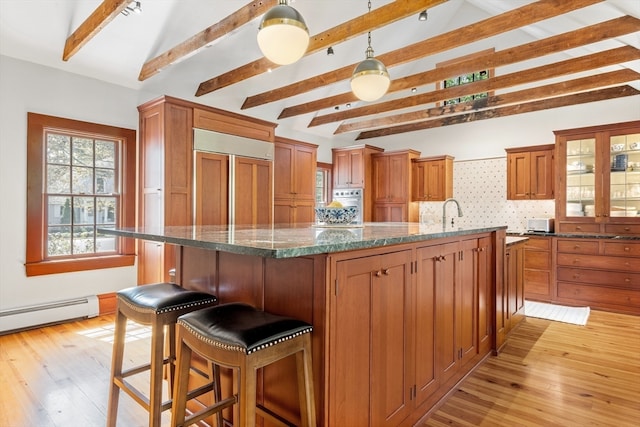 kitchen with a center island, light hardwood / wood-style flooring, paneled built in fridge, and dark stone countertops