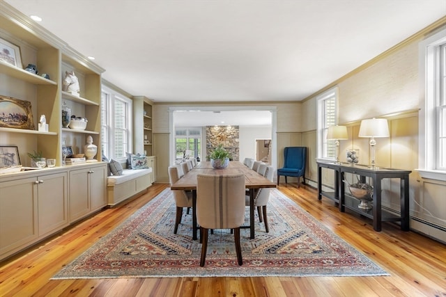 dining space featuring light hardwood / wood-style floors, ornamental molding, and built in features