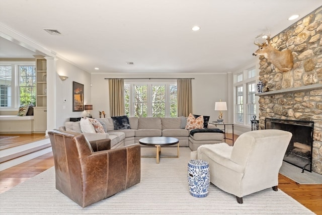 living room with ornamental molding, light wood-type flooring, and a healthy amount of sunlight