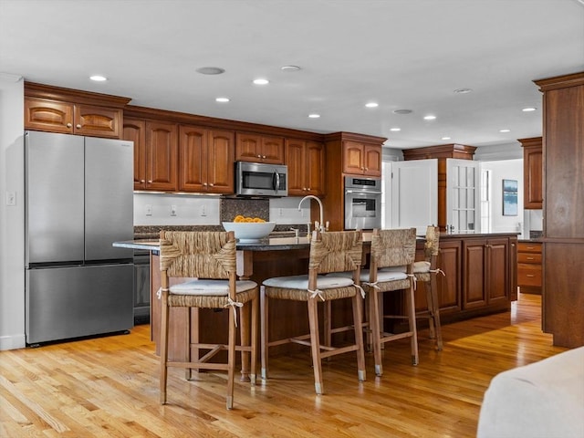 kitchen featuring light wood-style flooring, appliances with stainless steel finishes, and a breakfast bar