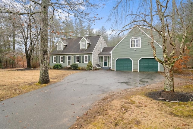 cape cod home featuring a garage and aphalt driveway