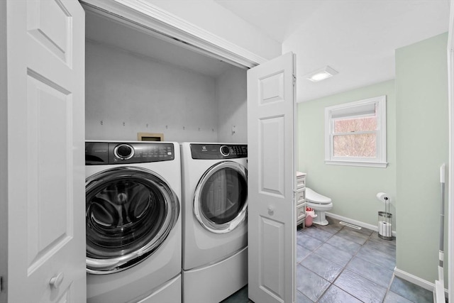 washroom featuring laundry area, separate washer and dryer, and baseboards