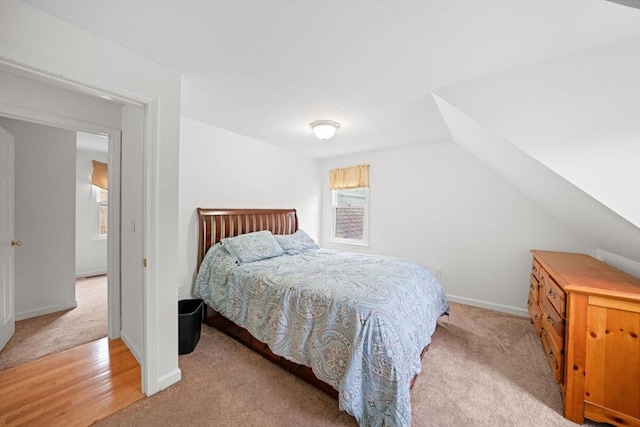 bedroom featuring baseboards, vaulted ceiling, and light colored carpet