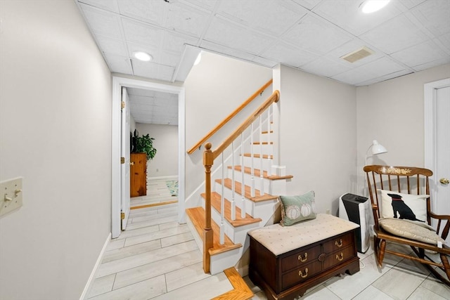 stairs featuring visible vents, a drop ceiling, and baseboards