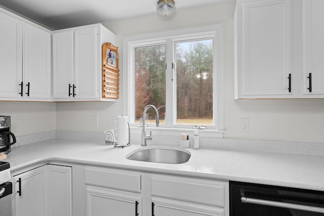 kitchen with a wealth of natural light, white cabinetry, a sink, and dishwashing machine