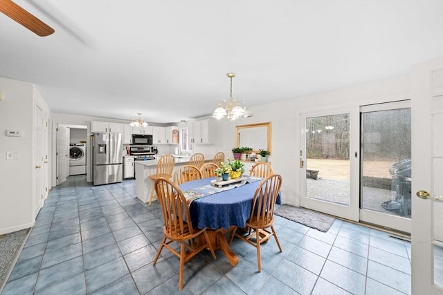 dining room featuring a chandelier, washer / clothes dryer, light tile patterned floors, and baseboards