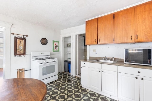 78 Endicott St, Peabody, MA 01960 - kitchen with white gas range, a sink, a textured ceiling, and white cabinets