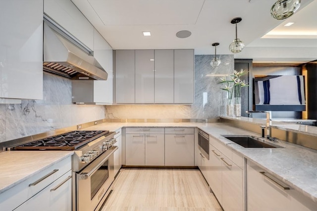 kitchen featuring sink, tasteful backsplash, decorative light fixtures, and high end stainless steel range