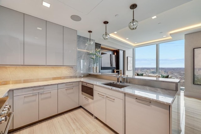 kitchen featuring stainless steel stove, sink, decorative light fixtures, kitchen peninsula, and light stone counters