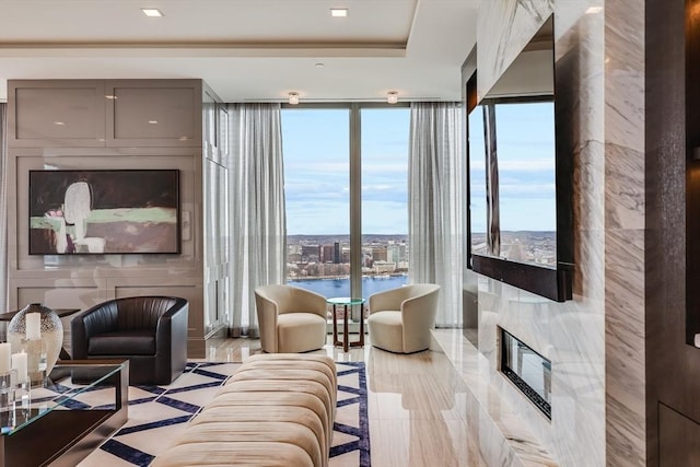 living room featuring a healthy amount of sunlight, a water view, expansive windows, and a high end fireplace