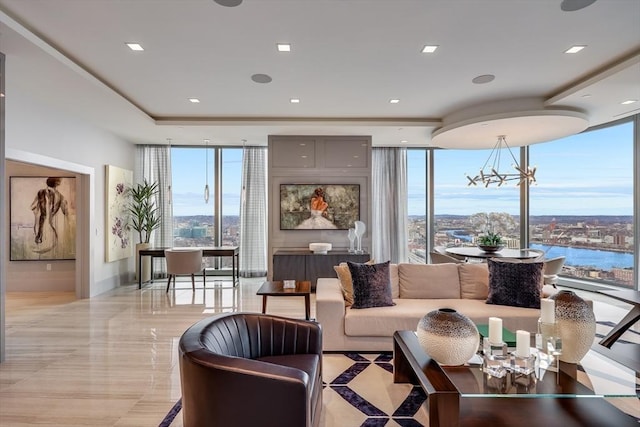 living room featuring a wall of windows, a water view, a healthy amount of sunlight, and an inviting chandelier