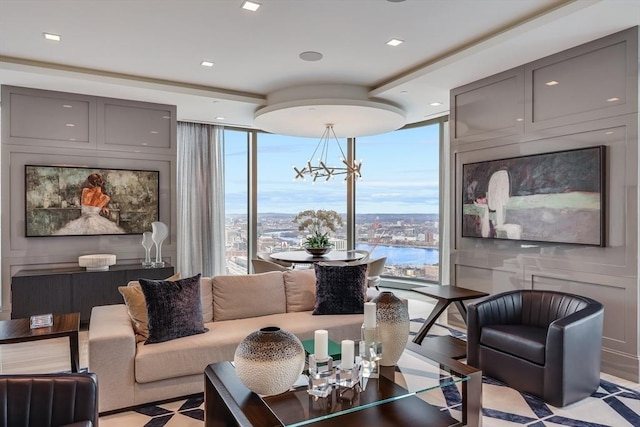 living room with a wealth of natural light, a wall of windows, a notable chandelier, and a water view