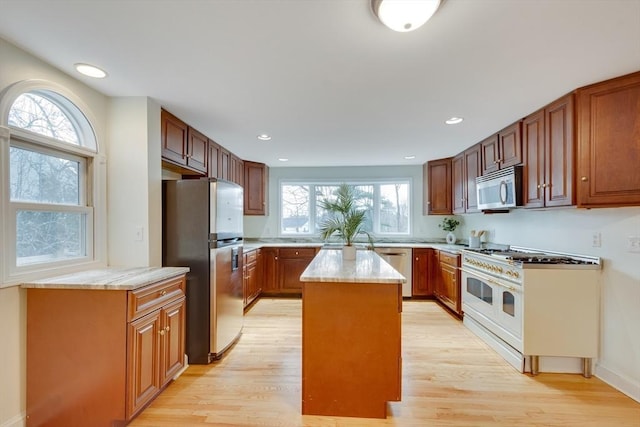 kitchen featuring light stone counters, light hardwood / wood-style flooring, a kitchen island, and appliances with stainless steel finishes