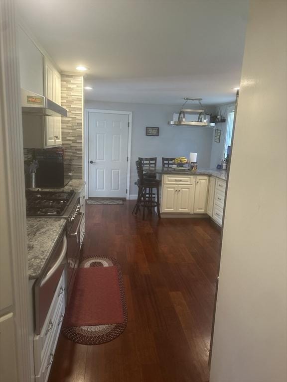 kitchen featuring dark wood-style flooring, white cabinets, backsplash, recessed lighting, and light stone countertops