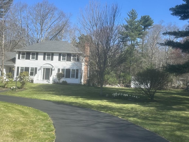colonial house featuring a chimney and a front lawn