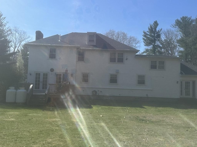back of property with french doors, a yard, a wooden deck, and a chimney