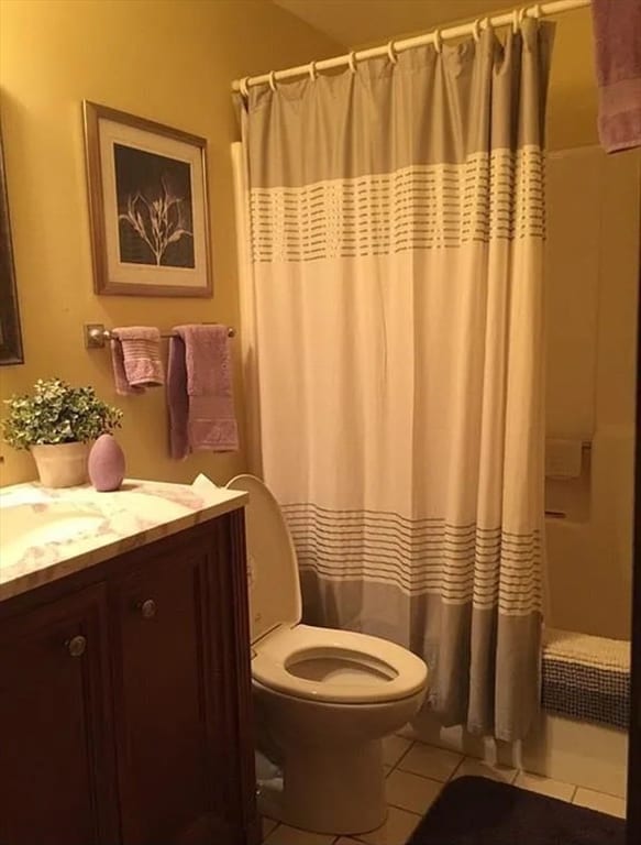 bathroom featuring curtained shower, tile patterned flooring, vanity, and toilet