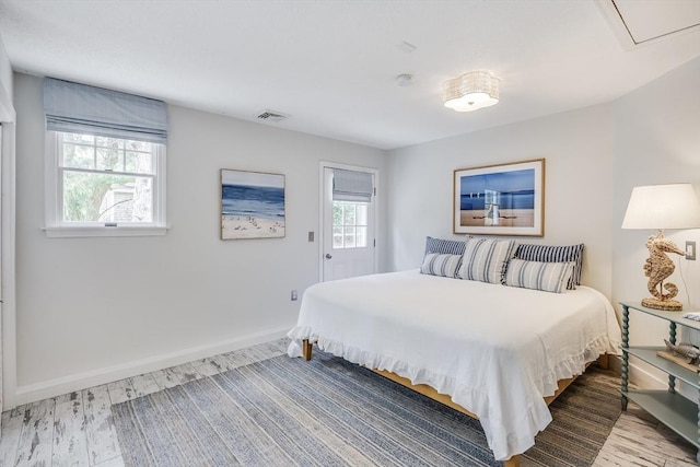bedroom featuring wood finished floors, baseboards, and attic access