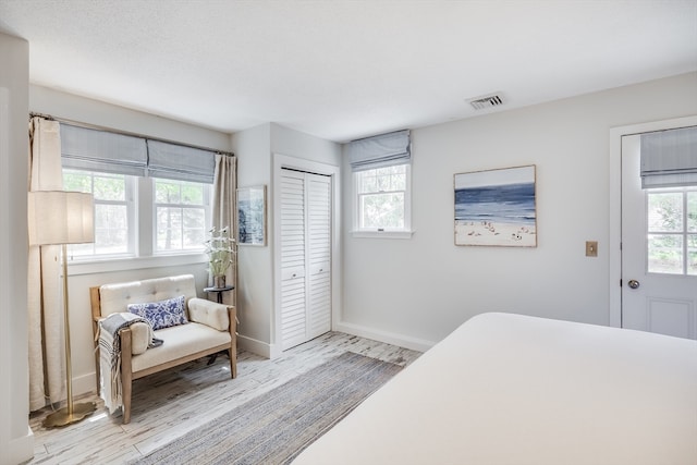 bedroom featuring multiple windows, wood finished floors, baseboards, and a closet
