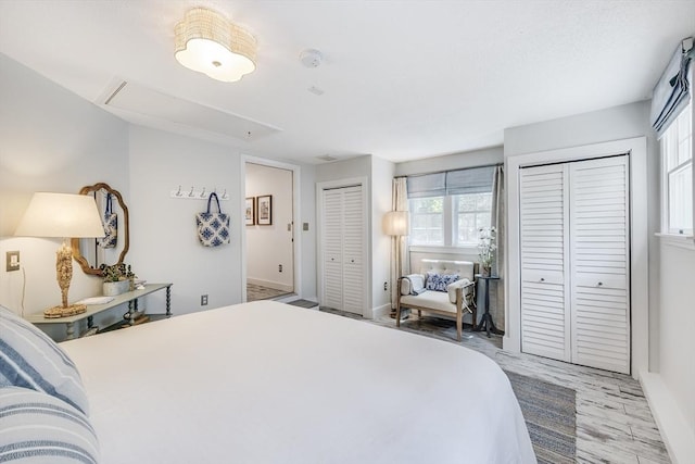 bedroom featuring multiple closets, attic access, and baseboards