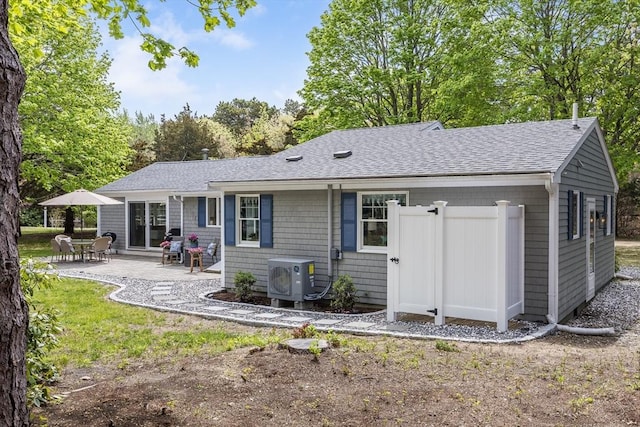 back of house with ac unit, a shingled roof, and a patio