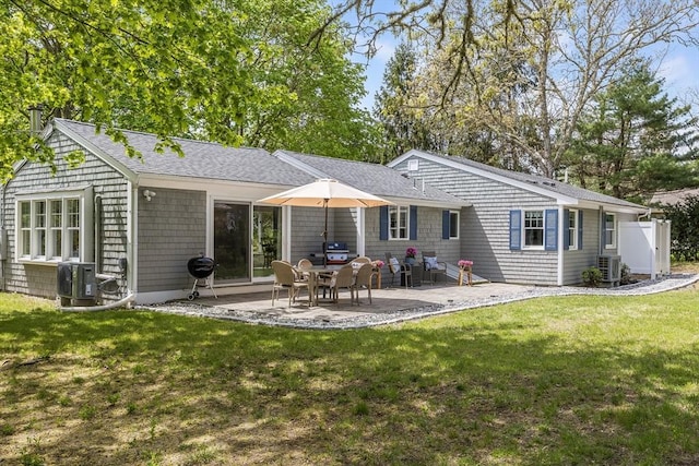 back of house with central air condition unit, a patio, a yard, and roof with shingles