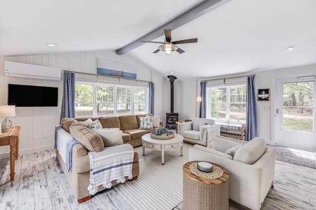 living area featuring a wood stove, a wall mounted AC, healthy amount of natural light, and a ceiling fan