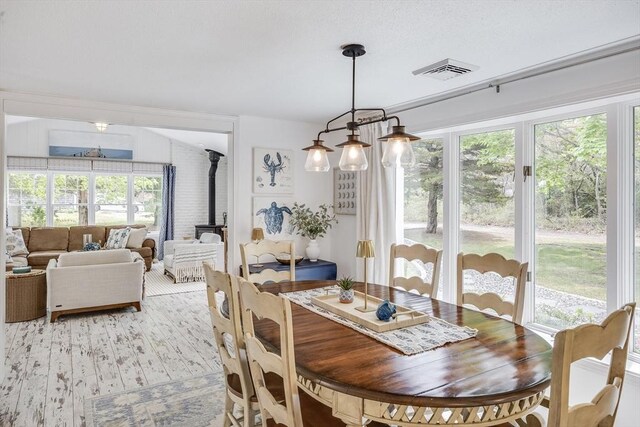 dining area with a wood stove, healthy amount of natural light, and light wood-style floors