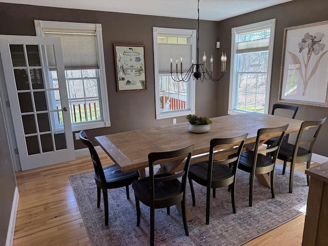 dining room featuring light wood-style floors, baseboards, and an inviting chandelier