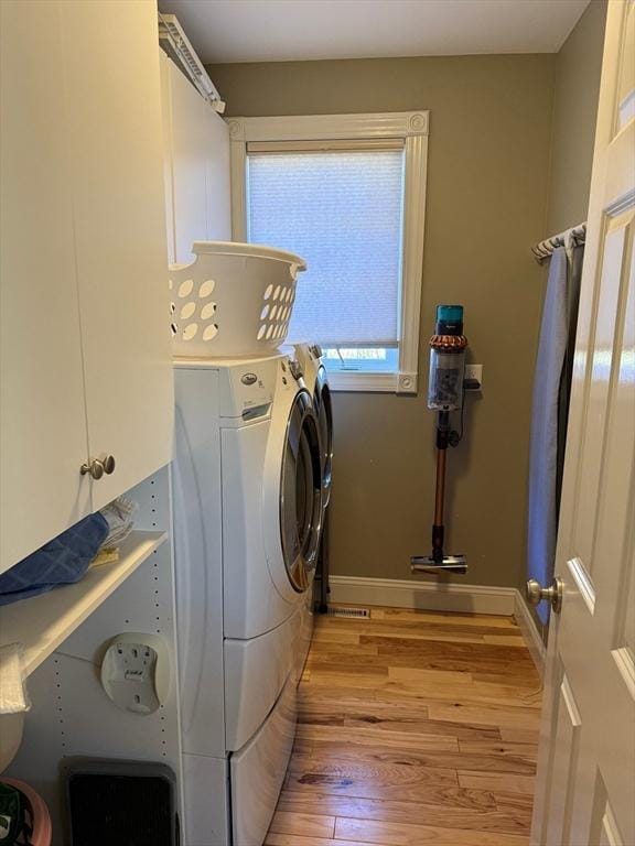 laundry area with light wood-style floors, washing machine and dryer, baseboards, and cabinet space