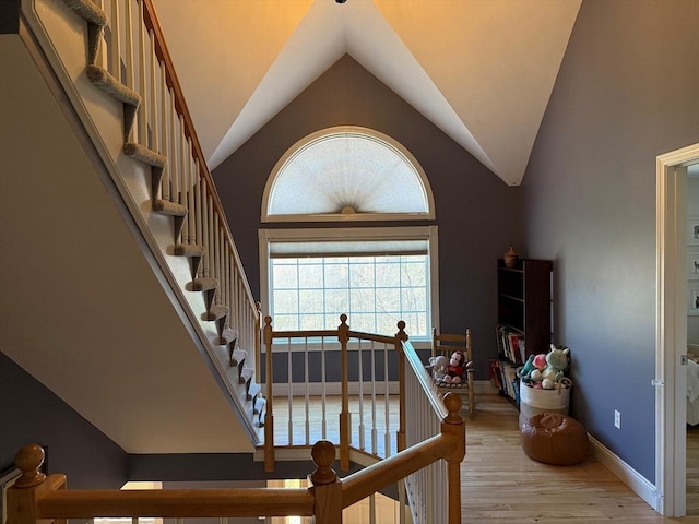 stairs with wood finished floors, baseboards, and vaulted ceiling
