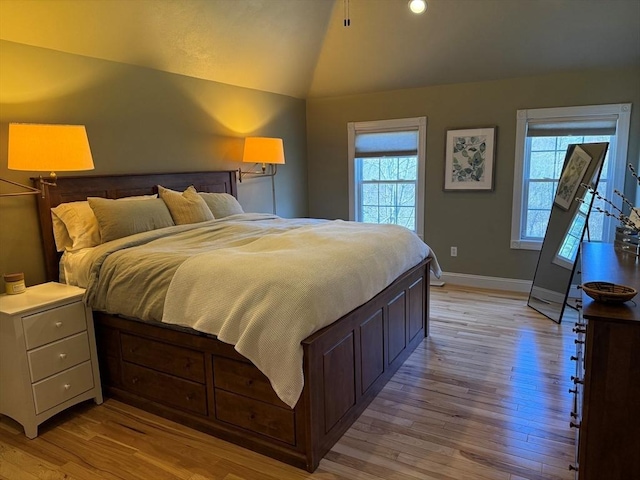 bedroom featuring light wood-type flooring, baseboards, and lofted ceiling